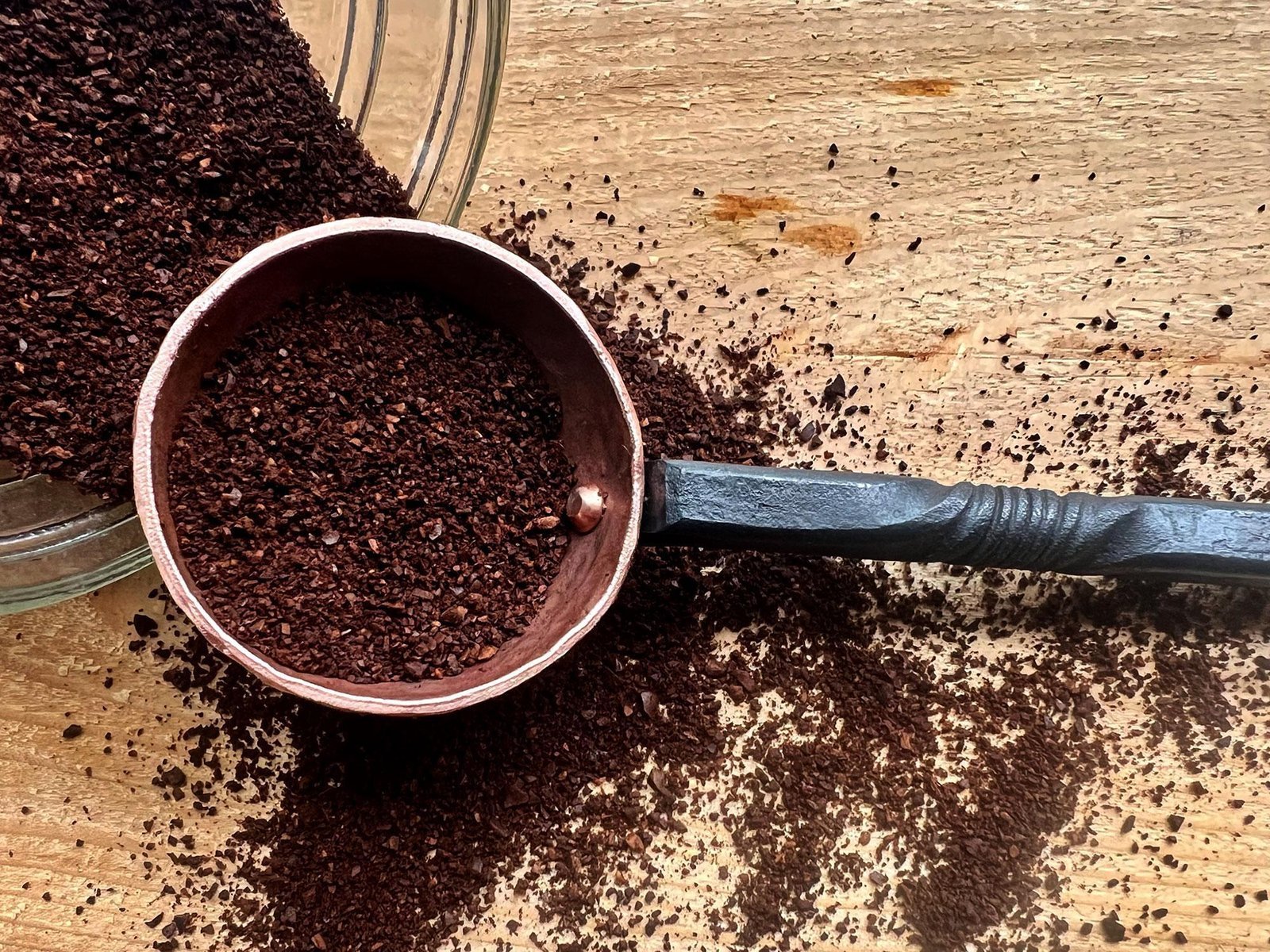 A small jar of ground coffee on a desk next to a notebook.