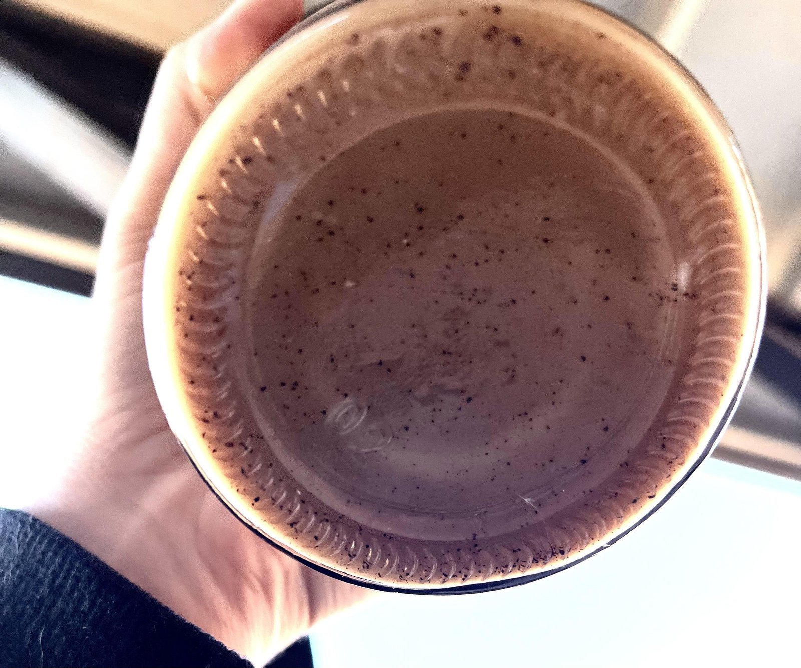 Close-up of coffee grounds settling inside a glass French press carafe.