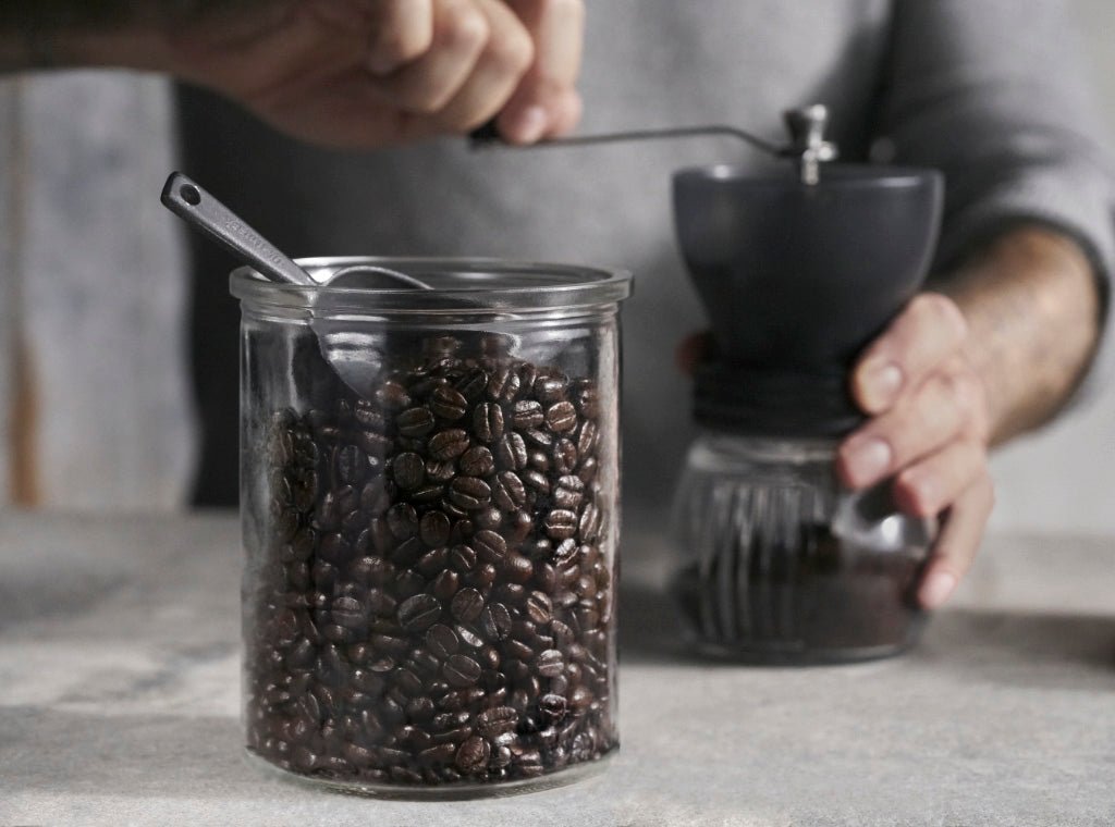 A stainless steel Moka pot ready for brewing on a wooden table.