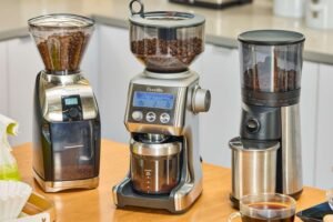 A coffee grinder and coffee beans on a kitchen counter for brewing coffee.