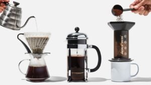 A collection of coffee brewing tools and ground coffee on a wooden table.