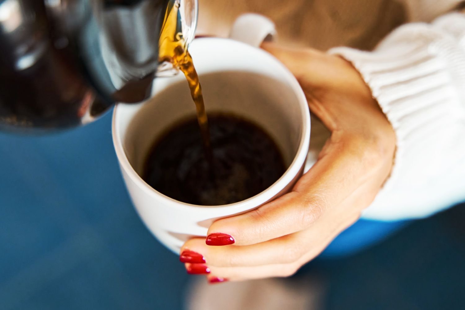 A steaming cup of coffee sitting on a desk with a notebook for questions.