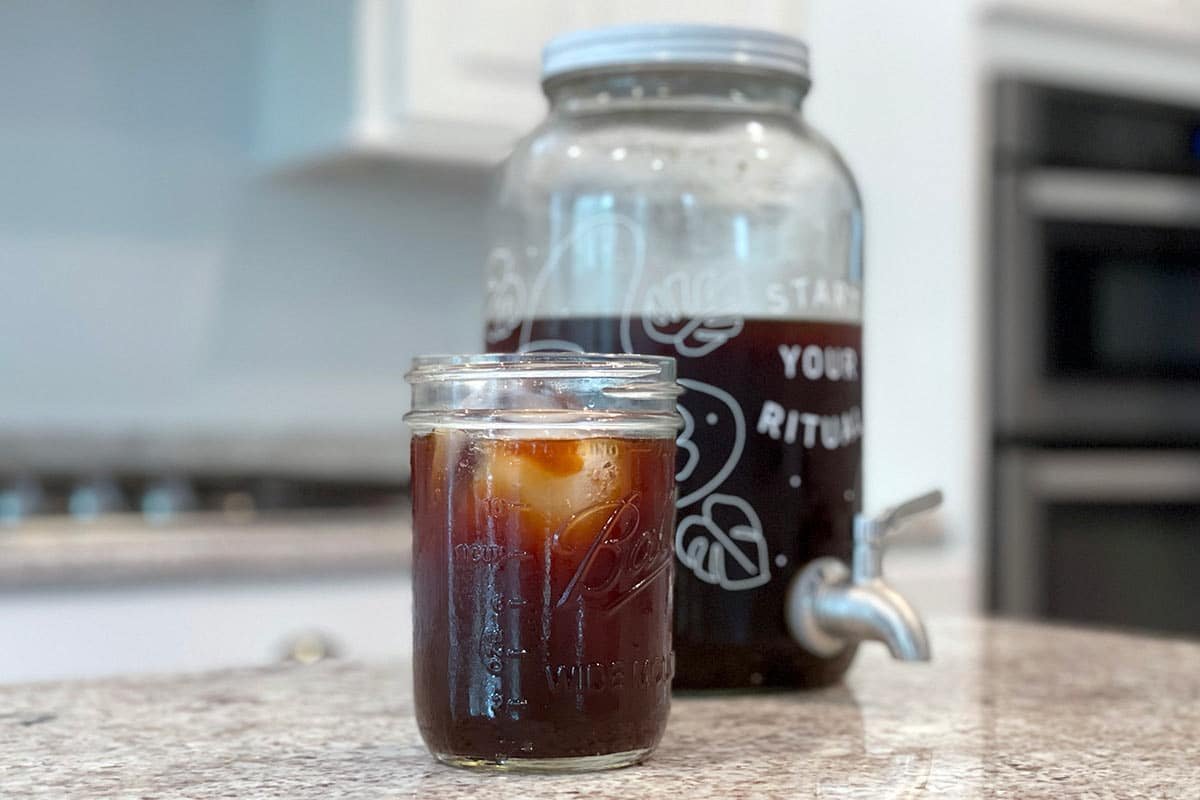 A glass of perfectly brewed cold brew concentrate next to a prepared serving.