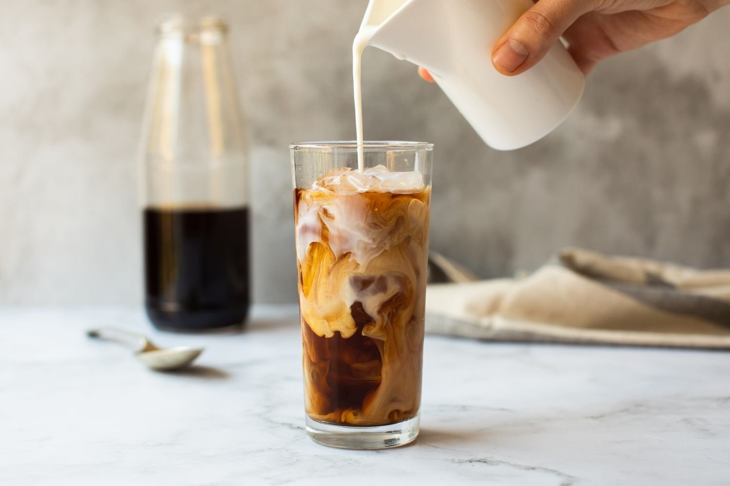 A glass of refreshing cold brewed iced coffee on a wooden kitchen table.