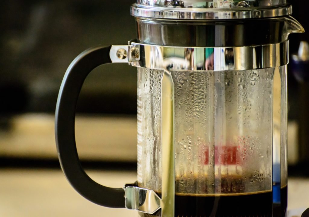 A glass cup filled with dark, opaque coffee showing a successful manual brew.