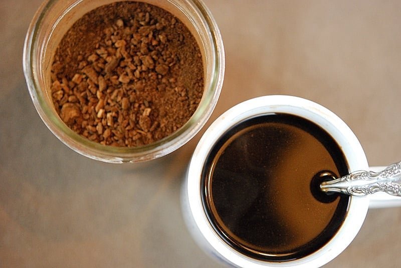 A glass carafe of fresh coffee sitting on a clean marble countertop.
