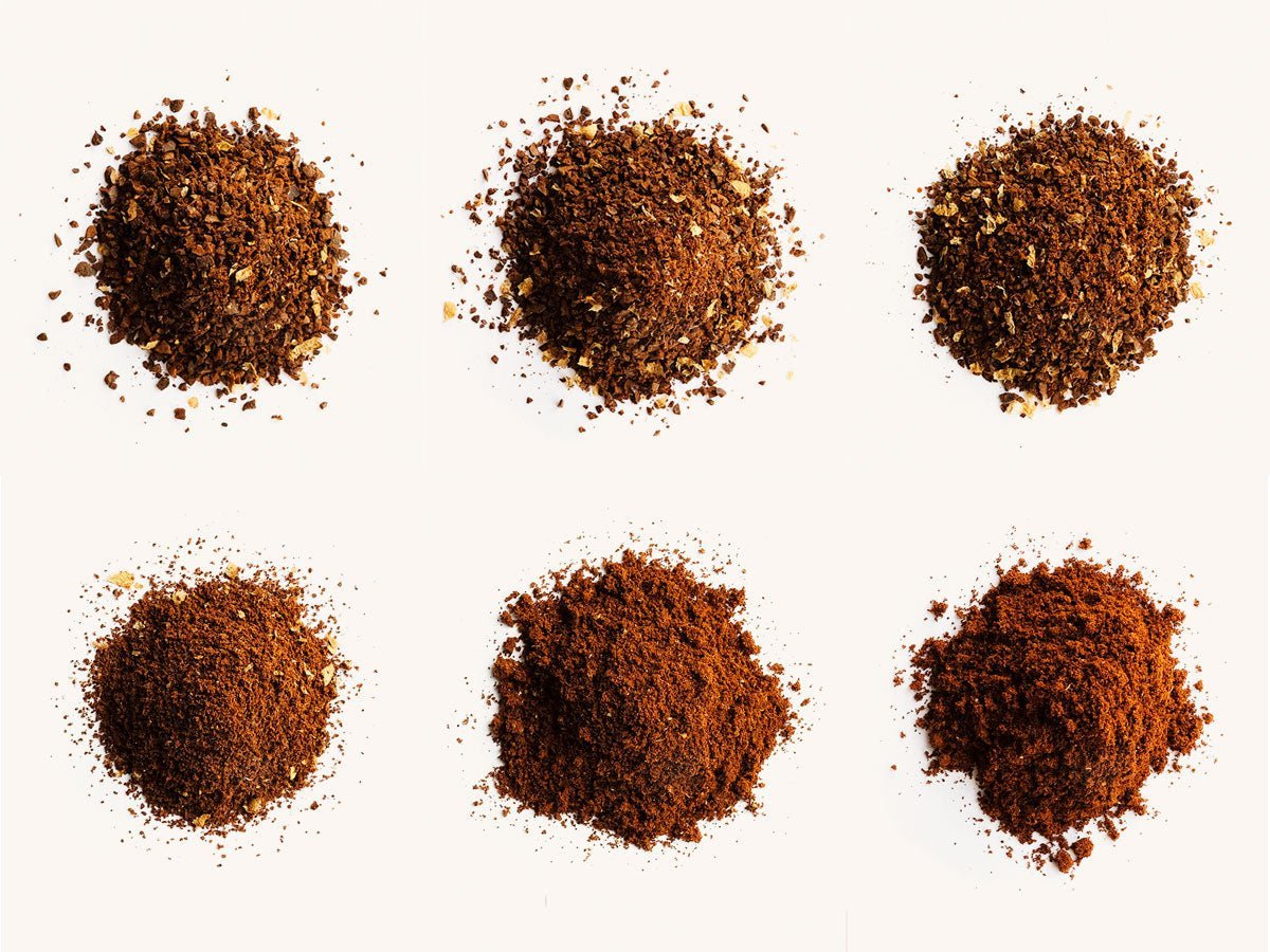 Freshly processed coffee grinds sitting on a digital scale next to a grinder.