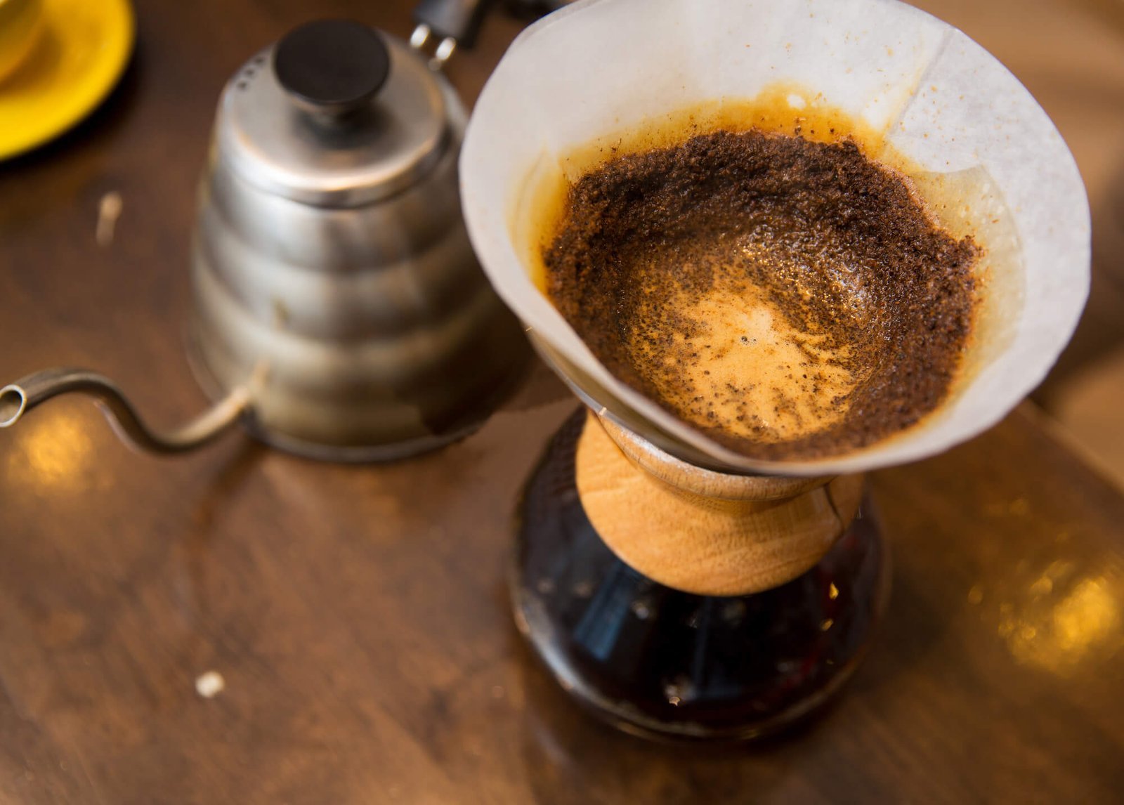 A wooden scoop measuring coffee grounds next to a digital scale on a counter.