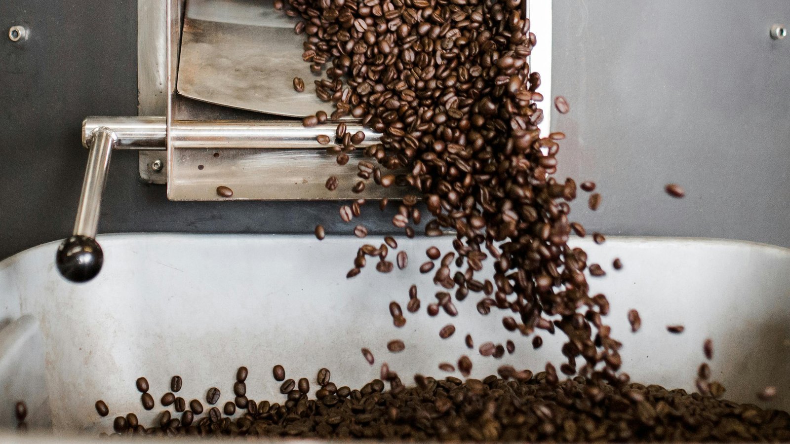 A steaming mug of medium roast coffee surrounded by fresh roasted beans.