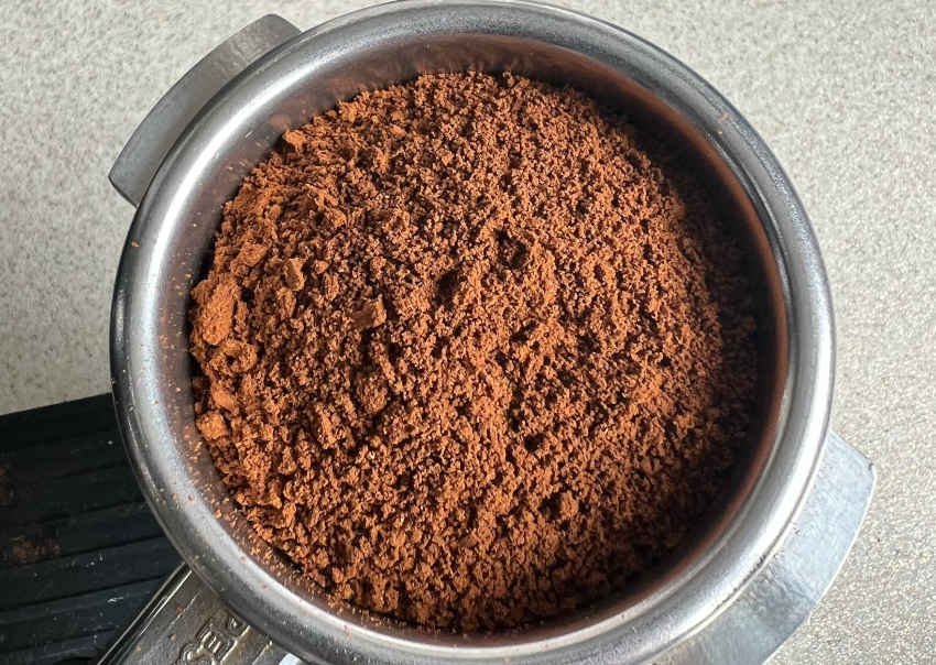 A variety of ground coffee textures arranged on a clean white kitchen surface.