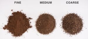 A pile of medium grind coffee beans resting on a wooden table.