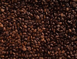 Freshly ground coffee beans arranged on a white marble surface for brewing.