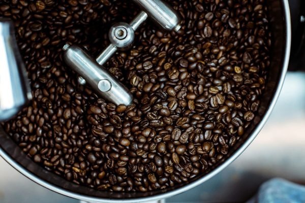 A barista holding a bag of fresh roasted coffee beans in a cafe.