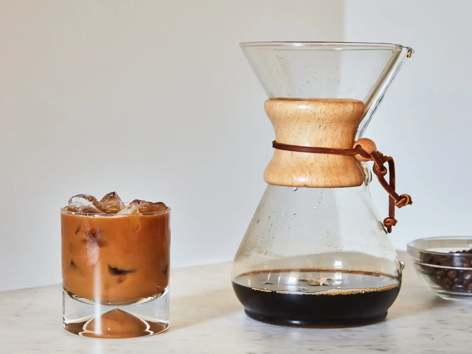 Dark oversteeped cold brew coffee pitcher next to spent wet grounds