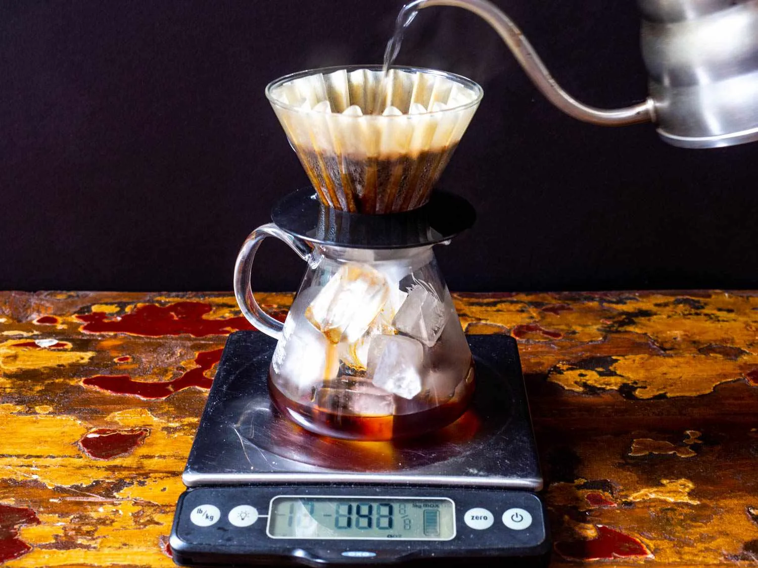 Hands pouring over-steeped cold brew coffee through a paper filter.