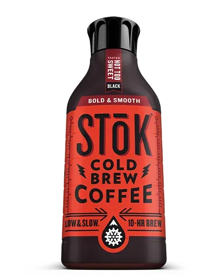 Opened bottle of spoiled cold brew coffee sitting on a bare counter.