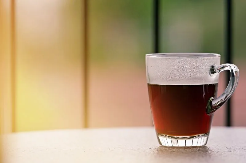 Pouring cold brew coffee into a ceramic mug on a wooden table.