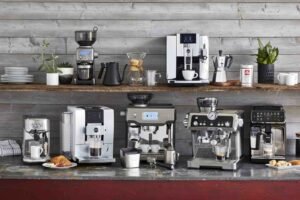 Stainless steel espresso machine on a marble counter with roasted coffee beans.
