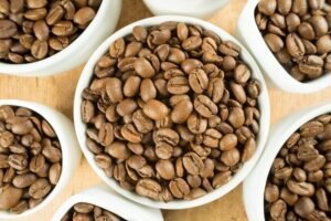 Top-down view of light roast coffee beans and brewing equipment on wood.