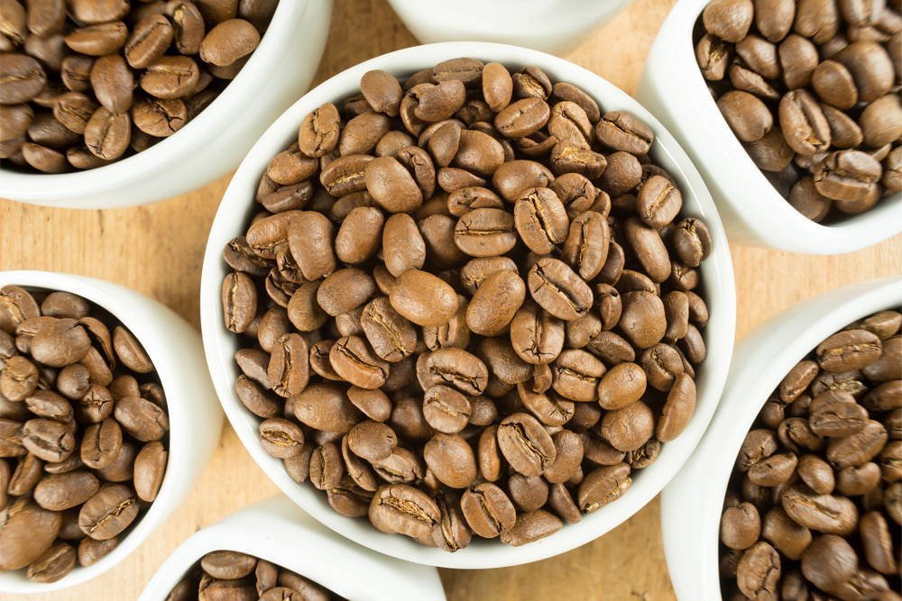 Top-down view of light roast coffee beans and brewing equipment on wood.