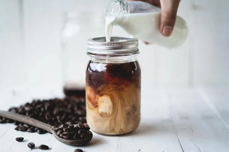 Two mugs of warmed cold brew coffee on a bright marble counter.